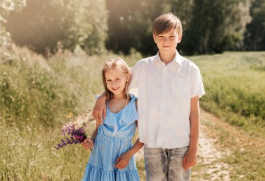 Oğlan ve kız kardeş yazın doğada sarılırlar.