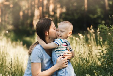 Genç bir anne kollarına alır ve yazın doğada küçük bir çocuğa sarılır.