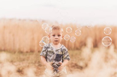 Yazın küçük bir çocuk sabun köpüğüyle oynuyor.
