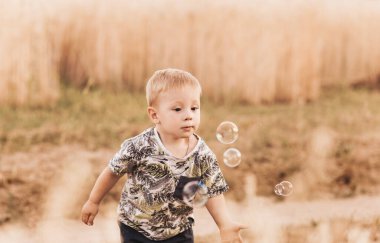 Yazın küçük bir çocuk sabun köpüğüyle oynuyor.
