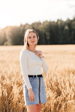 Kot etekli güzel bir kız güneşli bir günde buğday tarlasında yürüyor.