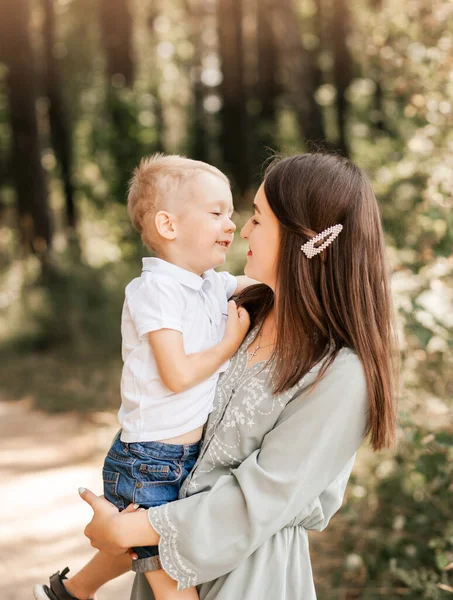 Genç ve güzel bir anne küçük oğlunu kollarına alır ve yazın doğada onunla oynar..