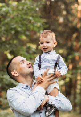 Genç bir baba ve genç oğlu yazın doğada. Sarıl ve öp.