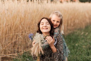 Büyük ve küçük kız kardeşler yazın doğada birlikte yürürler. kız kardeş sarılır ve sakinleşir.
