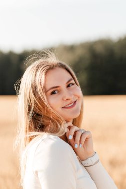 Kot etekli güzel bir kız güneşli bir günde buğday tarlasında yürüyor.