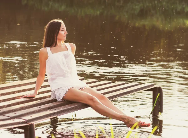 Junges Mädchen sitzt am Ufer des Flusses — Stockfoto