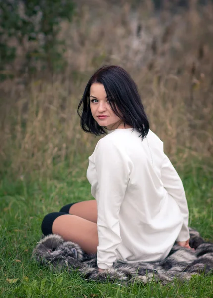 Jonge vrouw zittend op het gras — Stockfoto