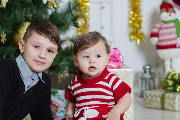 Niño y niña cerca de un árbol de Navidad —  Fotos de Stock