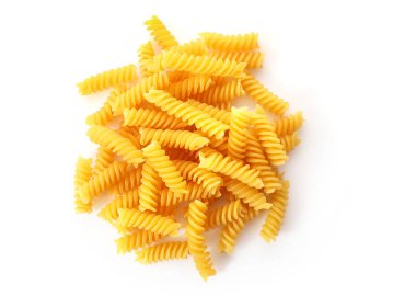 Beyaz zemin üzerinde izole edilmiş çiğ fusilli makarna yığını. Üst görünüm.