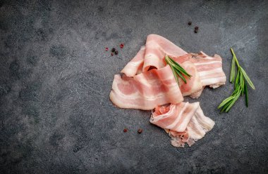 Çiğ pastırma dilimleri ve siyah arka planda biberiye filizi. Üst Manzara. Boşluğu kopyala.