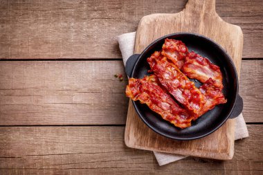 Tahta arka planda tavada kızarmış pastırma dilimleri. Üst Manzara. Boşluğu kopyala.