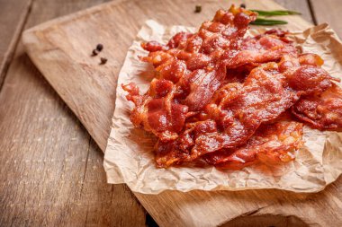 Kızarmış pastırma dilimleri ve ahşap arka planda kraft kağıdında biberiye filizi..