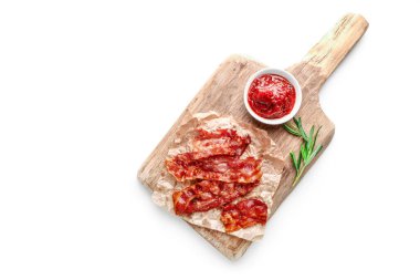 Kızarmış domuz pastırması, biberiye filizi ve domates sosu beyaz arka planda küçük kasede. Üst görünüm.