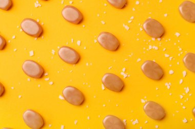 Sarı arkaplanda tuzlu karamel şekeri deseni.