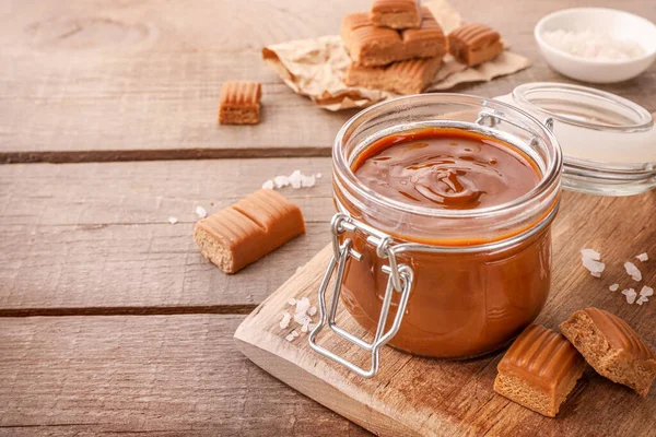 Geschmolzenes Karamell Glas Mit Gesalzenen Karamellbonbons Auf Holzgrund — Stockfoto