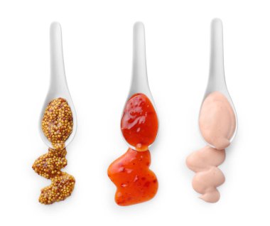 Beyaz arka planda izole edilmiş kaşıklardan dökülen soslar. Üst görünüm.