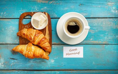 Taze kruvasan ve koyu kahve mavi ahşap arka planda izole edilmiş. Üst görünüm.