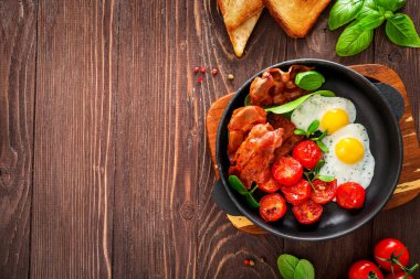 Tam Amerikan kahvaltısı, kızarmış yumurta ve ahşap arka planda kızarmış pastırma. Üst Manzara. Boşluğu kopyala.