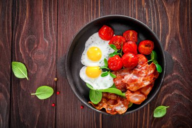 Tam Amerikan kahvaltısı, kızarmış yumurta ve ahşap arka planda kızarmış pastırma. Üst görünüm.