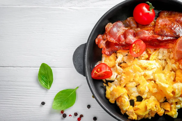 American breakfast with scrambled eggs and roasted bacon on white background. Top view. Close-up.
