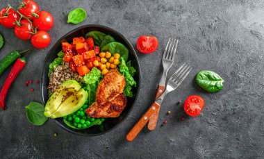 Kinoa, avokado, terli patates, kızarmış tavuk ve koyu arkaplanlı baharatla nefis bir öğle yemeği. Üst görünüm.
