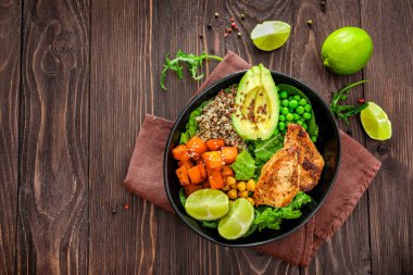 Kinoa, avokado, terli patates, kızarmış tavuk ve ahşap arka planda baharatla nefis bir öğle yemeği. Üst görünüm.