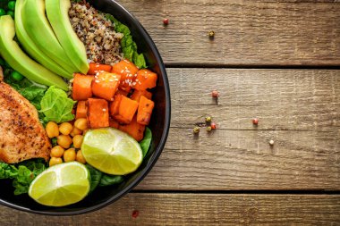 Kinoa, avokado, terli patates, kızarmış tavuk ve ahşap arka planda baharatla nefis bir öğle yemeği. Üst görünüm.