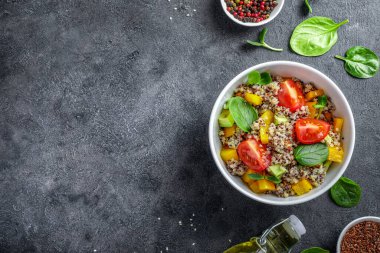 Siyah arka planda domatesli kinoa salatası, batata ve ıspanak. Vegan gıda konsepti. Üst Manzara. Boşluğu kopyala.