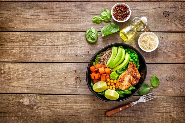 Kinoa, avokado, terli patates, kızarmış tavuk ve ahşap arka planda baharatla nefis bir öğle yemeği. Üst Manzara. Boşluğu kopyala.