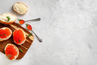 Beyaz zemin üzerinde kırmızı havyarla dilimler halinde tahta kesme tahtası. Üst Manzara. Boşluğu kopyala.