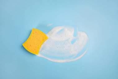 Sarı kauçuk eldiven duvarları turuncu yumuşak bir bezle yıkar, duvarları temizler ve yıkar, mavi arka plan fotokopi alanı, temizlik konsepti, bahar temizliği, ev işi konsepti