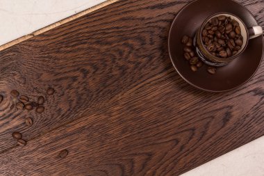 Karanlık bir parke üzerinde kahve çekirdekleri ile kahverengi Kupası