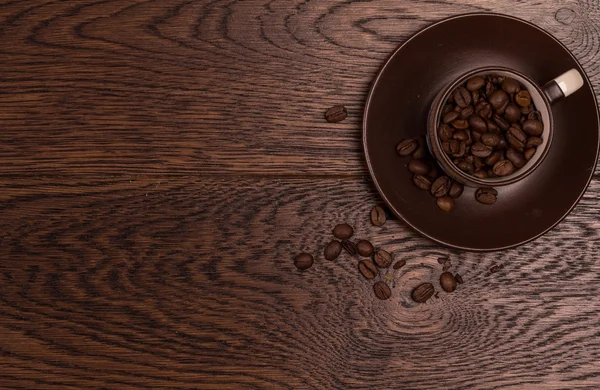 Karanlık bir parke üzerinde kahve çekirdekleri ile kahverengi Kupası