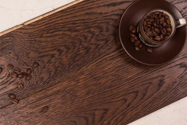 Karanlık bir parke üzerinde kahve çekirdekleri ile kahverengi Kupası