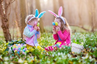 Kids on Easter egg hunt in blooming spring garden clipart