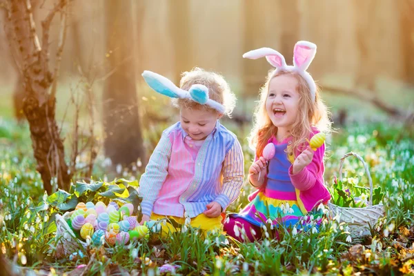 Copii la vânătoarea de ouă de Paște în grădina de primăvară înfloritoare . — Fotografie, imagine de stoc