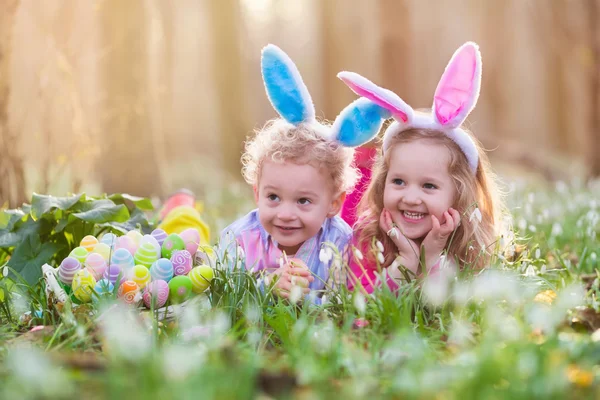 Kinderen op eieren zoeken met Pasen in de bloeiende lente tuin — Stockfoto