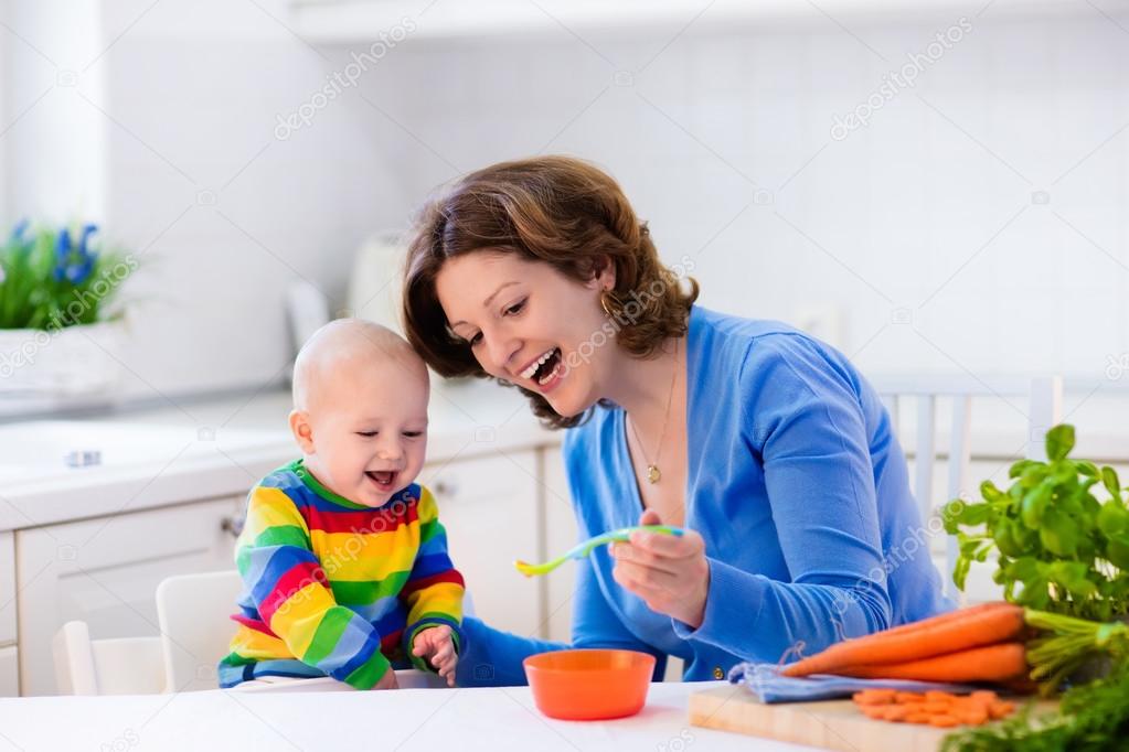 Mother feeding baby first solid food