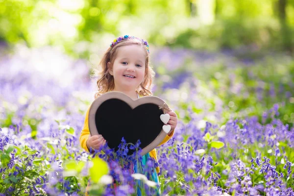 Niña con tablero en blanco en el campo de flores —  Fotos de Stock