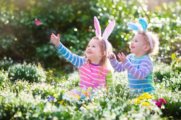 Kinderen op eieren zoeken met Pasen in de bloeiende lente tuin — Stockfoto