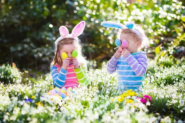 Crianças na caça ao ovo de Páscoa no jardim de primavera florescendo — Fotografia de Stock