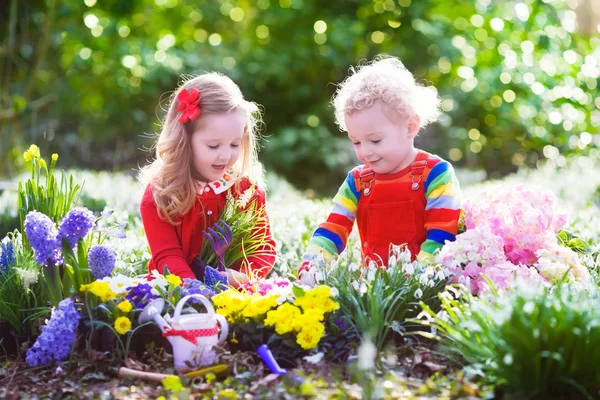 Enfants plantant des fleurs dans le jardin fleuri — Photo