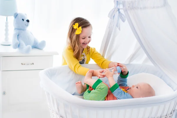 Little girl giving baby brother bottle with milk — Φωτογραφία Αρχείου