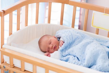 Newborn baby boy in hospital cot clipart