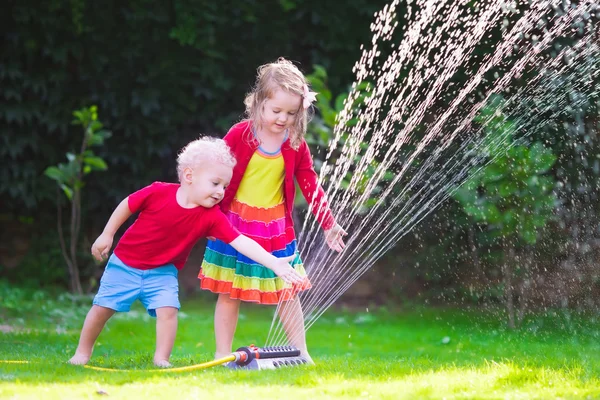 Niños jugando con aspersor de jardín — Foto de Stock