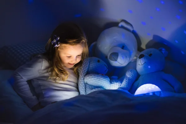 读一本书躺在床上的小女孩 — 图库照片