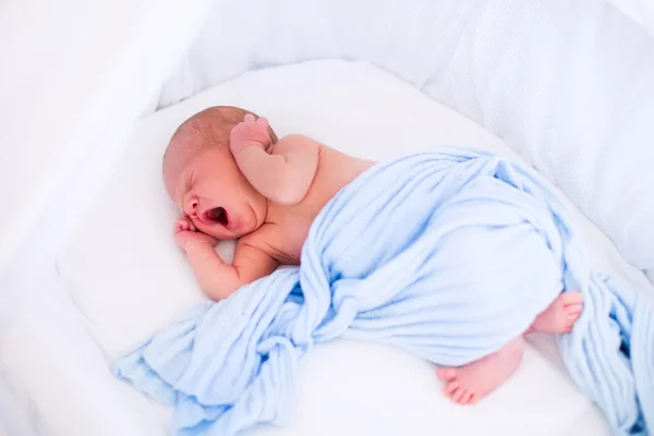 Cute yawning newborn baby in white bed — 스톡 사진