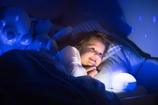Маленькая девочка читает книгу в постели — стоковое фото