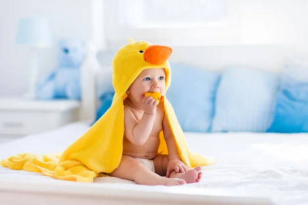 Симпатичный ребенок после ванны в желтом полотенце с уткой — стоковое фото