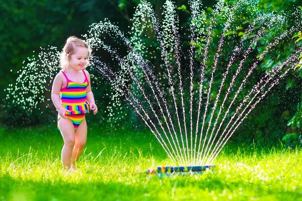 Menina brincando com aspersor de água do jardim — Fotografia de Stock